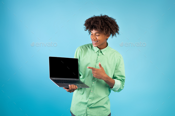 Great website. Teen african american guy showing laptop computer blank screen