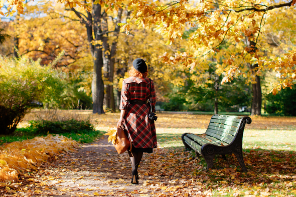 redhead woman in plaid coat and beret walks through the park at sunny day, back view. fall season - Stock Photo - Images