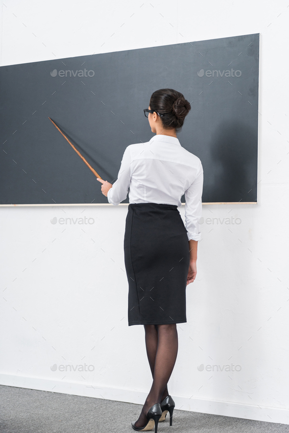 young attractive teacher pointing at blank chalkboard