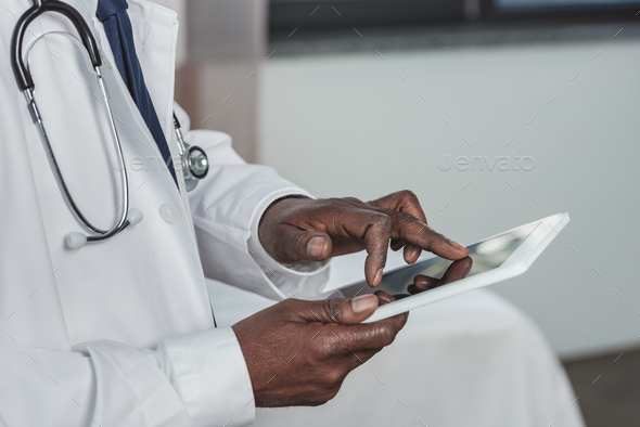 Cropped image of african american doctor searching something on a tablet