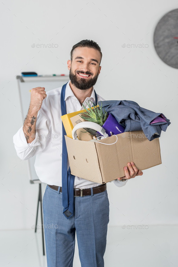 portrait of smiling businessman with cardboard box in hands quitting job