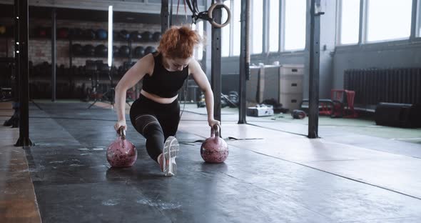 Young Professional Athletic Red Haired Coach Woman Doing Split Stretch Exercise on Kettlebells in alt