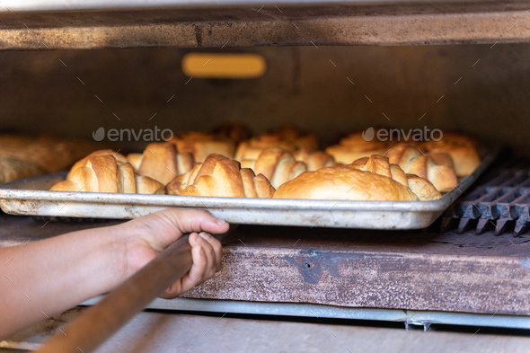 Person taking pastries out of an industrial oven