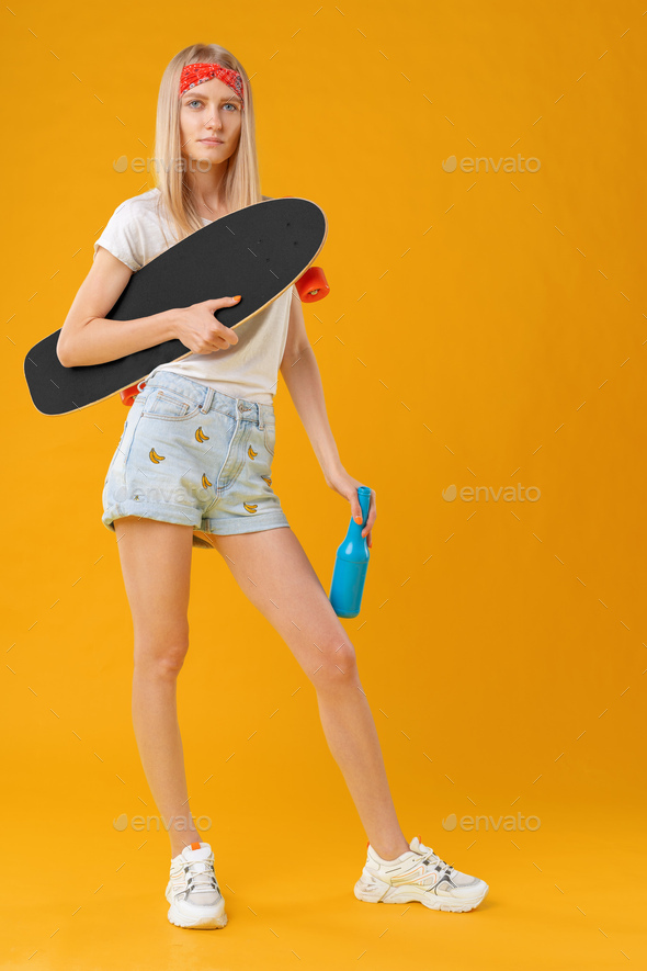 Portrait of a young girl in short shorts with longboard - Stock Photo - Images