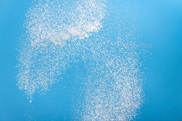 White powder splashes isolated on blue background. Flour sifting on a blue background