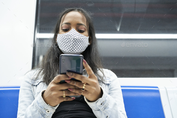 Close up of black woman sitting alone in the subway car using a smartphone