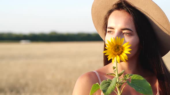 Young Brunette with Sunflower in Field