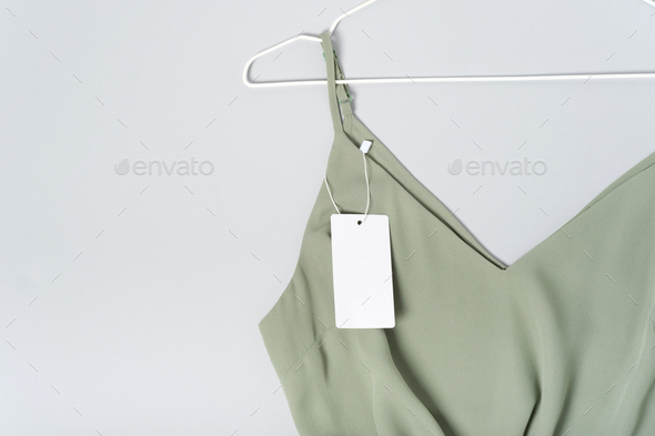 White clothing tag, label blank mockup, to place your design. Cotton khaki green blouse, hanger
