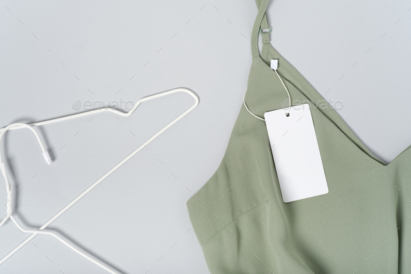 White clothing tag, label blank mockup, to place your design. Cotton khaki green blouse, hangers