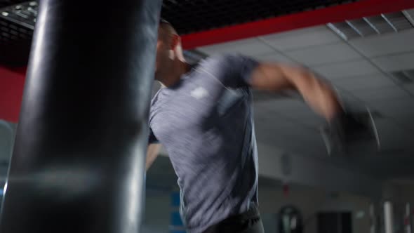 Confident Motivated Male Boxer Hitting Punching Bag in Gym Training alt