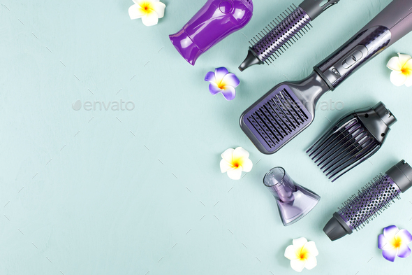 Hairdressing tools border with flowers on blue wooden background