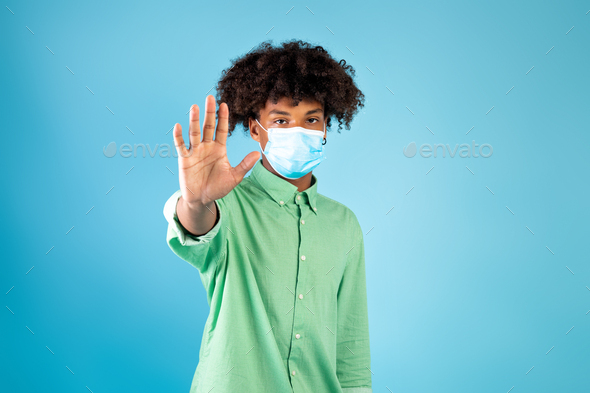 Teen black guy in face mask gesturing STOP, expressing negativity towards coronavirus pandemicon