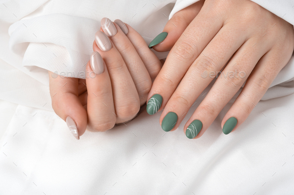 Hands of a young woman with green olive matte nails and beige glossy nails  on white background Stock Photo by marykor_ua