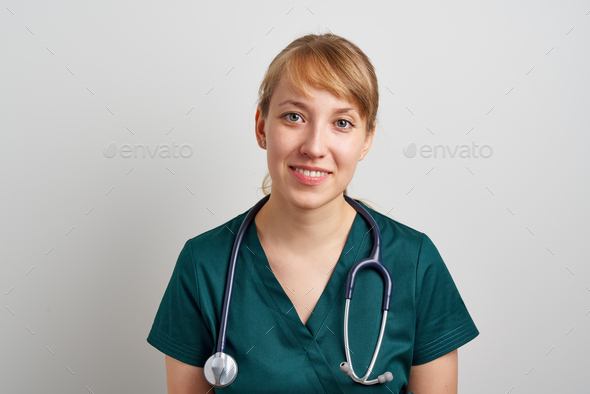 Smiling young female nursing assistant with phonendoscope in green uniform. Surgeon emergency