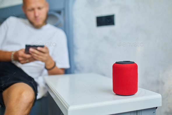Male testing talking smart wireless speaker, man controlling home devices with a voice commands