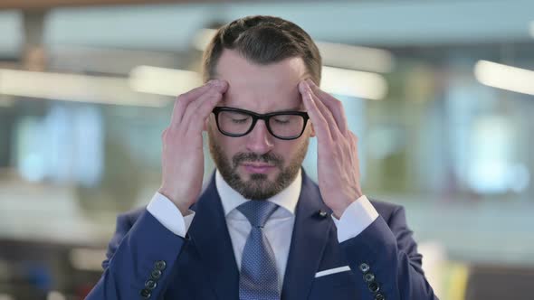 Portrait of Middle Aged Businessman Having Headache alt