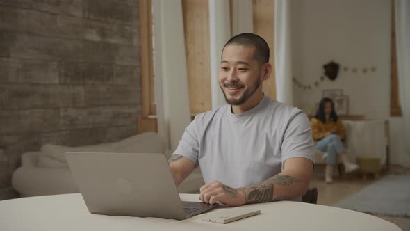 Close Up Portrait of a Young Adult Asian Man Recieving Good News on His Laptop Computer Indoors alt