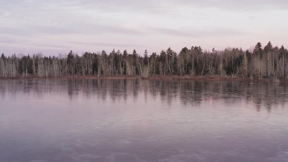 Spectacular aerial sunrise view of frozen lake shoreline within wilderness alt