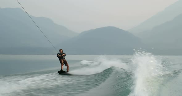 Front view of caucasian young man doing tricks on wakeboard in the city river 4k alt