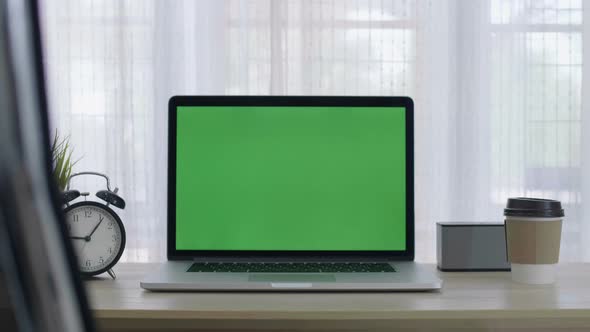 Chroma key green screen of laptop computer set on working space in home office alt