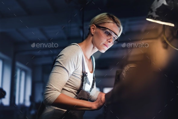 Portrait of mid adult industrial woman working indoors in metal workshop