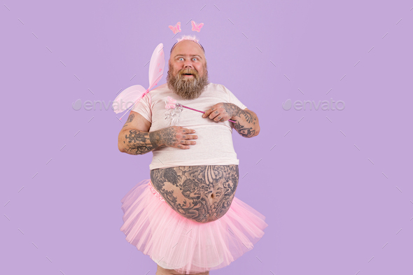 Bearded man with overweight in fairy suit with magic stick and wings on purple background