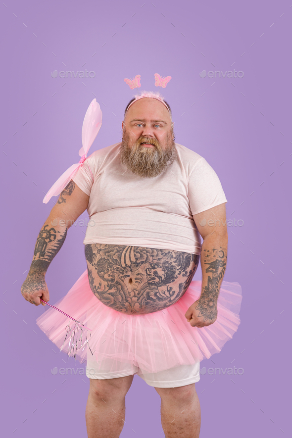 Funny brutal plus size man in fairy costume with magic stick and wings on purple background