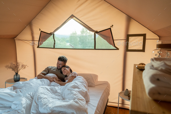 Affectionate couple looking at scenery around their glamping tent