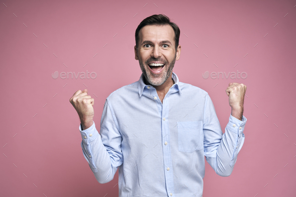 Studio shot of successful middle aged man celebrating achievement - Stock Photo - Images