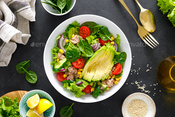 Avocado and tuna fresh vegetable salad with tomato, cucumber corn, onion, lettuce and spinach.