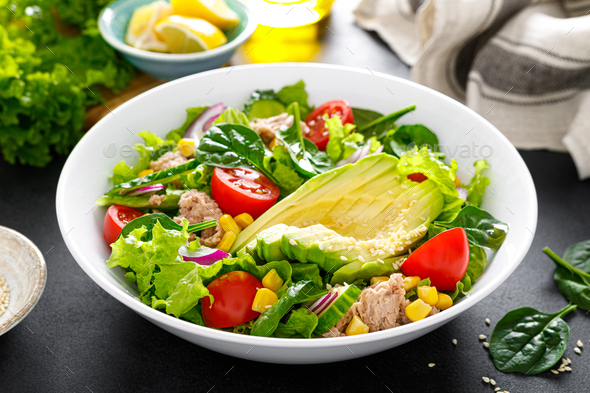 Avocado and tuna fresh vegetable salad with tomato, cucumber corn, onion, lettuce and spinach.