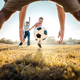 Kid kicking football ball while playing with his family - PhotoDune Item for Sale