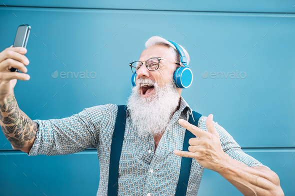 Senior crazy man taking self video while listening music with headphones