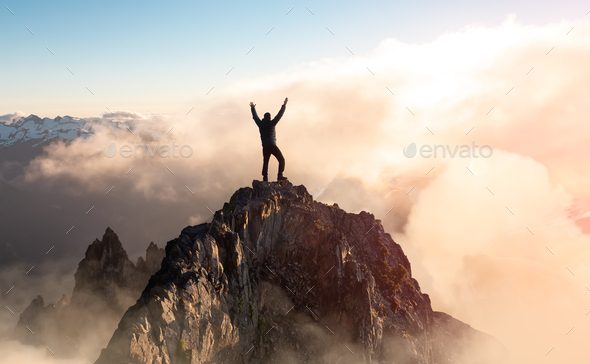 Adventurous Man with Open Hands is taking in the moment on top of a mountain