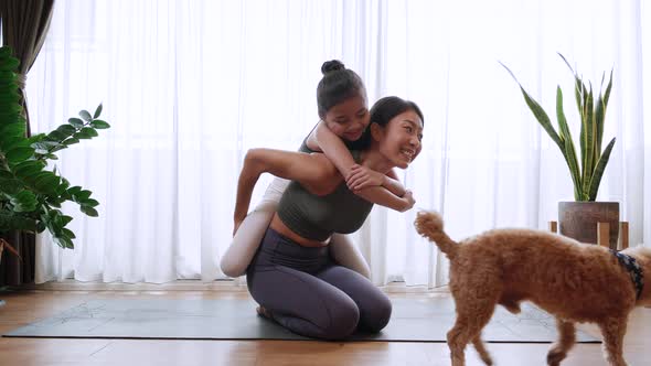 Healthy Little daughter enjoys riding the back of her mother during yoga exercise at home