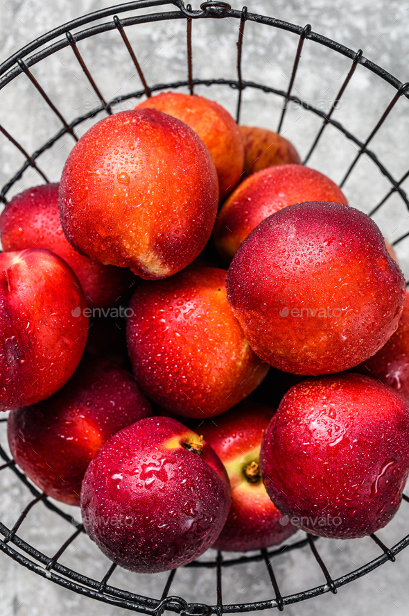 Fresh red nectarines in a steel basket. Gray background. Top view