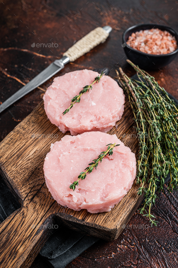 Fresh Raw burgers patty cutlet from chicken and turkey meat with herbs. Dark background. Top view
