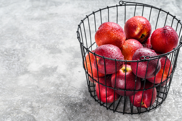 Fresh red nectarines in a steel basket. Gray background. Top view. Copy space