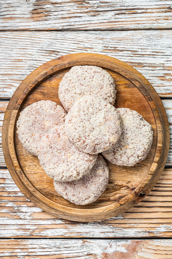 Raw chicken patty cutlet with breadcrumbs. White wooden background. Top view