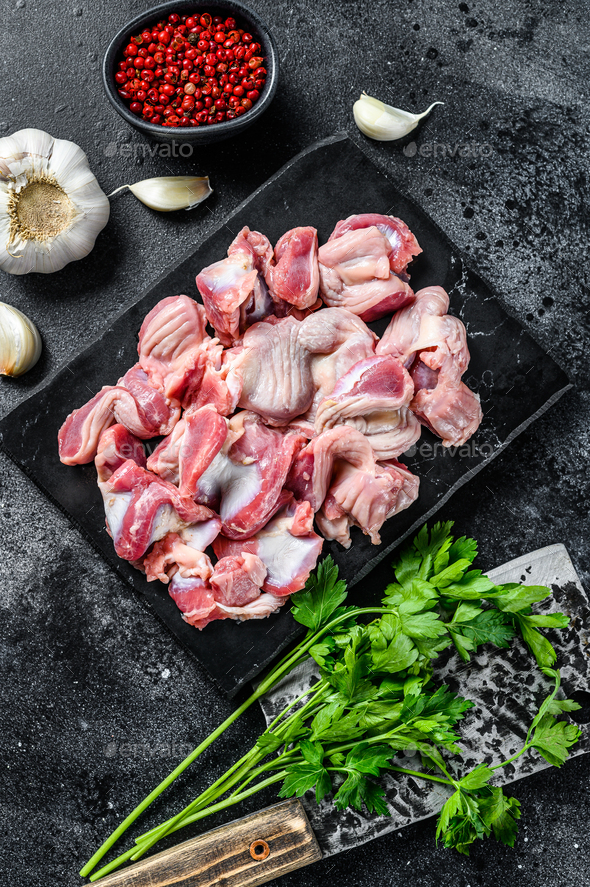 Raw uncooked Bird chicken giblets gizzards, stomachs. Black background
