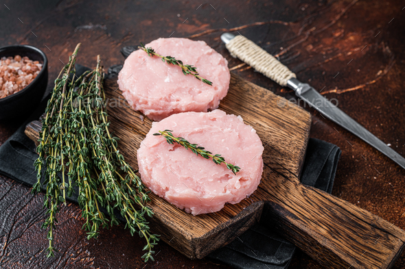 Fresh Raw burgers patty cutlet from chicken and turkey meat with herbs. Dark background. Top view