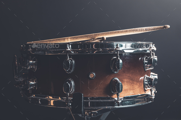 Close-up snare drum and drum sticks on a dark background.