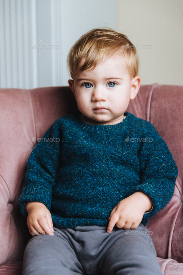 Cute small child with light hair and blue eyes, wears sweater and trousers,  has innocent expression Stock Photo by StudioVK