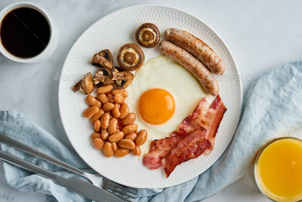 Classic english breakfast with eggs, sausages, becon, beans, mushrooms, coffee and orange juice
