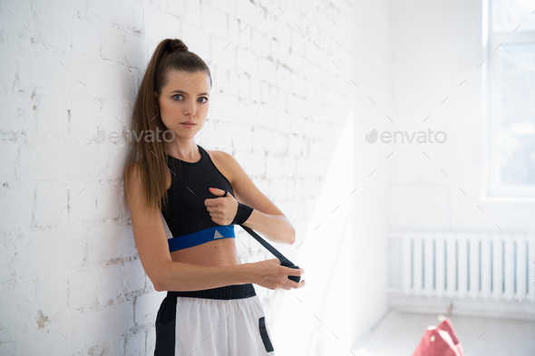 Close up of one young woman wrapping hands with black boxing wraps in gym practice boxing indoor - Stock Photo - Images