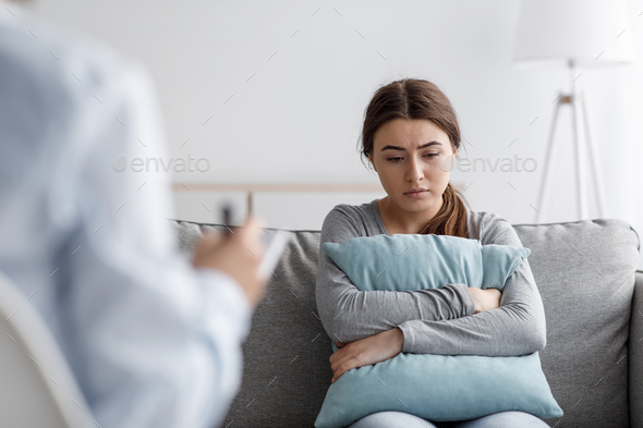 Sad european young woman suffering from depression and consults with psychologist in clinic