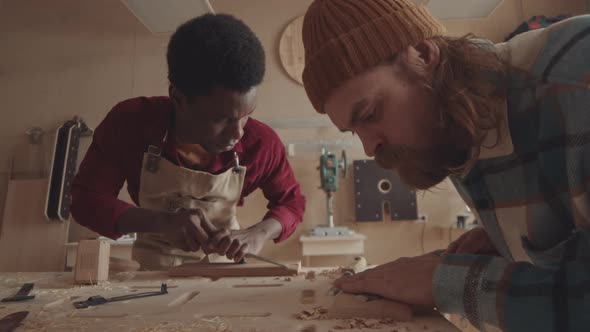 Pair of Multiethnic Joiners Carving Wooden Boards alt