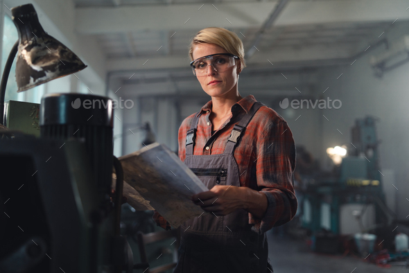 Portrait of young industrial woman working indoors in metal workshop