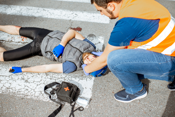 Road Accident With Injured Cyclist And Man Providing First Aid Stock ...