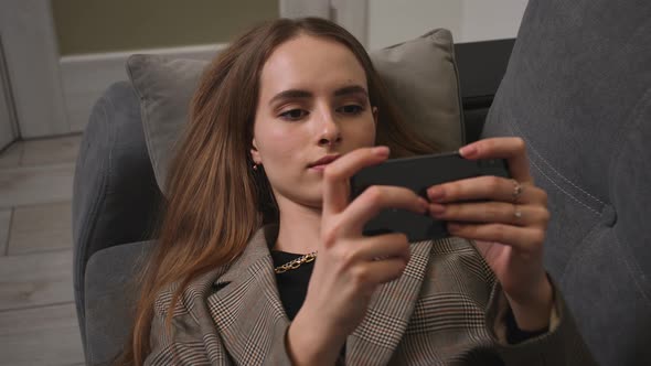 Relaxed Girl Holding Smartphone Using Mobile Apps Play Games Watching Video Lying on Couch at Home alt